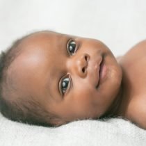 Dark skinned black baby smiling and lying down – Birth, Baby & You – Dee Bell – Lactation Consultant for Kent, Surrey & Sussex